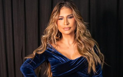 Simone Mendes posando com macacão de veludo azul-escuro, cabelo solto e feição séria