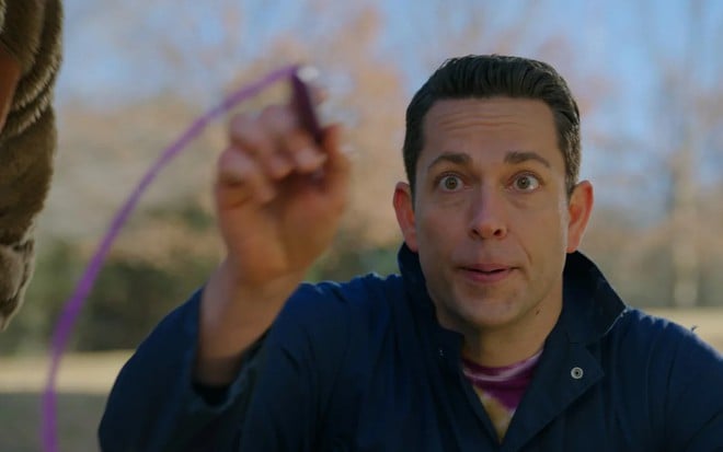 Zachary Levi tem expressão compenetrada enquanto desenha com um lápis roxo em uma tela invisível