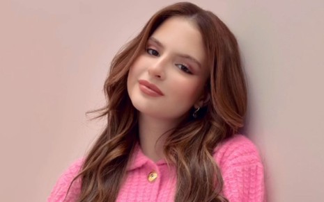 Sophia Valverde está com cabelos soltos e usa uma blusa rosa