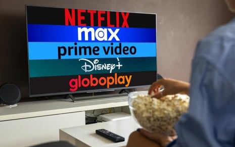 Imagem de uma pessoa na frente de uma TV, na tela do aparelho estão logos dos streamings Netflix, Max, Prime Video, Disney+ e Globoplay