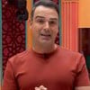 Foto mostra Tadeu Schmidt durante Big Brother Brasil; ele veste camiseta laranja