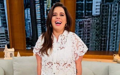 Tati Machado usa uma blusa rendada branca e sorri para a foto