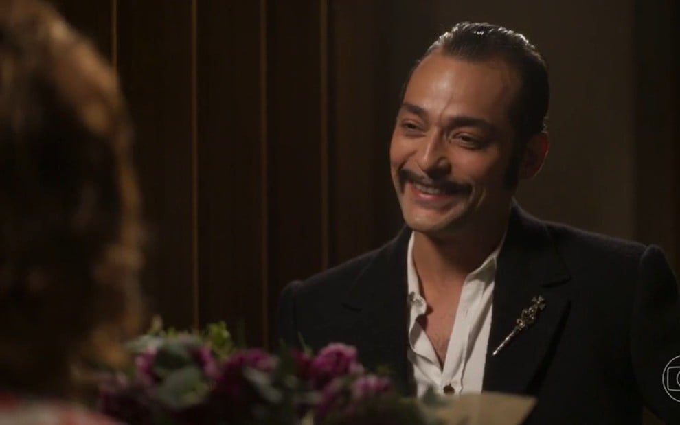 O ator Eduardo Sterblitch sorrindo, segurando buquê de flores, em frente à atriz Maria Eduarda de Carvalho em cena de Garota do Momento