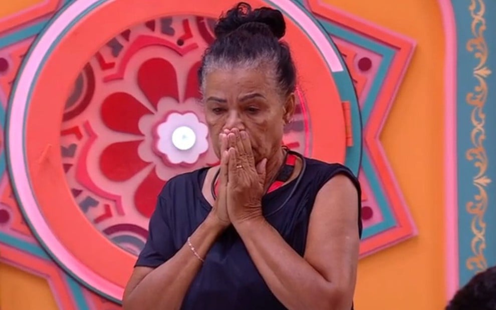 Vilma Nascimento está com as duas mãos na boca; ela está em pé na sala do BBB 25