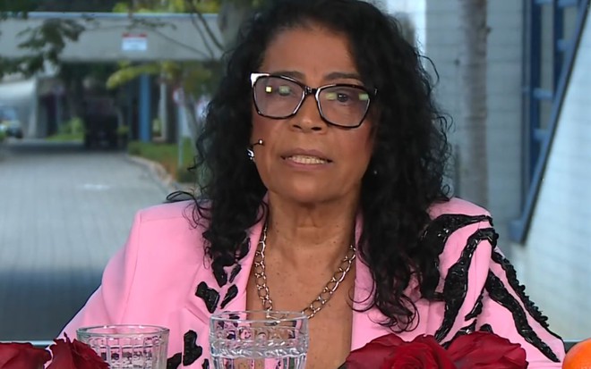 Vilma Nascimento no cenário do Café com Eliminado, do Mais Você, usando óculos e roupa rosa