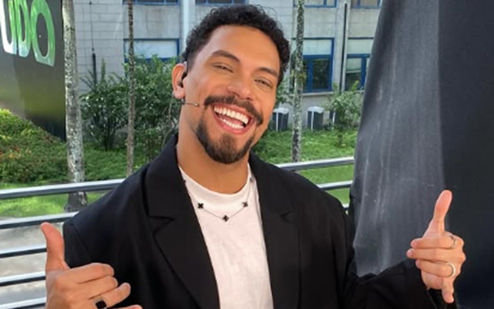 Vinícius Nascimento sorri e faz sinais de hang loose com as duas mãos