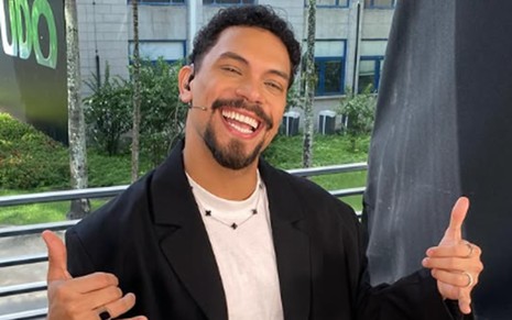 Vinícius Nascimento sorri e faz sinais de hang loose com as duas mãos