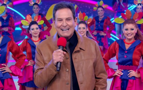 Luis Ricardo segura um microfone e está sorridente