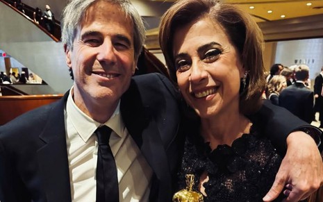 Walter Salles e Fernanda Torres lado a lado, sorridentes, enquanto a atriz segura a estatueta do Oscar