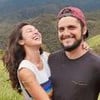 Os atores Yanna Lavigne e Bruno Gissoni abraçados e sorrindo no meio do mato