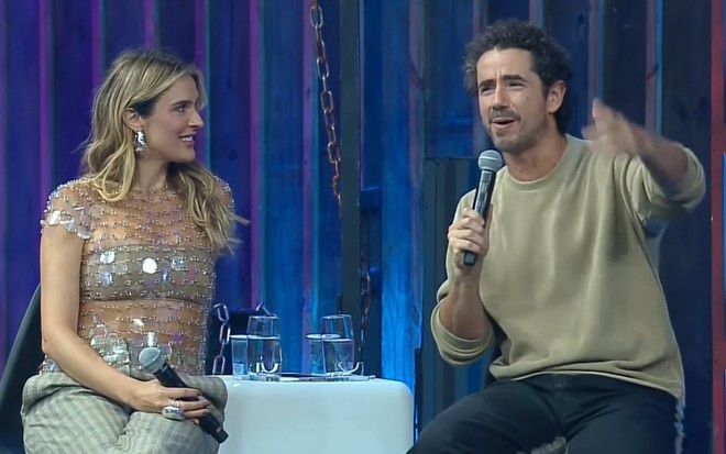 Rafa Brites e Felipe Andreoli discursam em um palco; ele sinaliza com as mãos enquanto segura o microfone com a outra