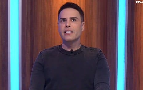 Luiz Bacci olha para cima e abre a boca em hesitação no cenário do Programa Flávio Ricco