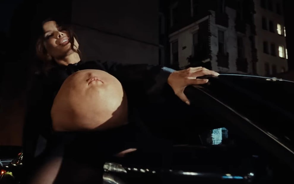 Com barriga imensa que tem uma boca no umbigo, Anitta sensualiza em carro no clipe de São Paulo