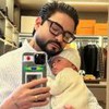 Yudi Tamashiro segurando o filho no colo e tirando uma foto no espelho