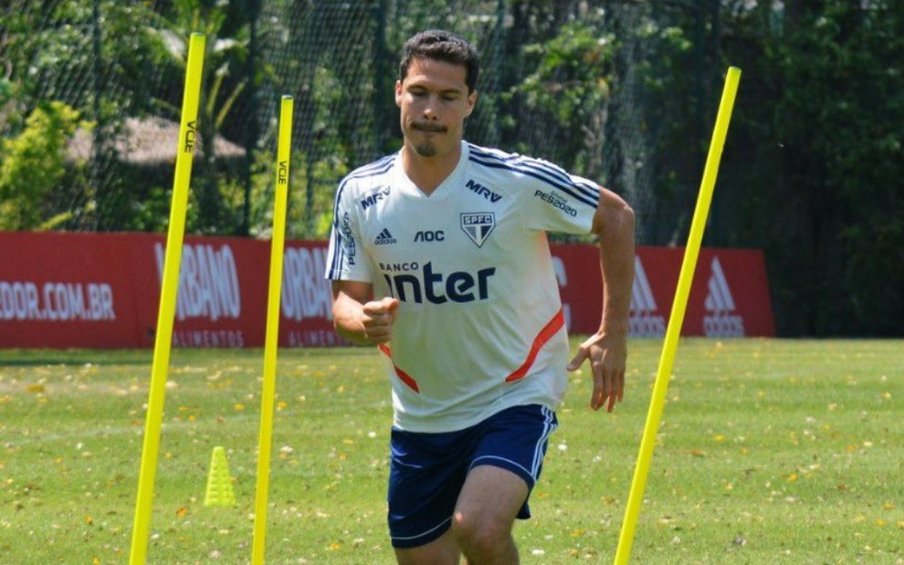 O jogador Hernanes veste o uniforme do São Paulo e corre entre obstáculos durante treino no campo de futebol