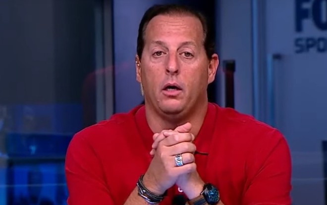 Benjamin Back com os braços apoiados na bancada do Fox Sports Rádio, do Fox Sports