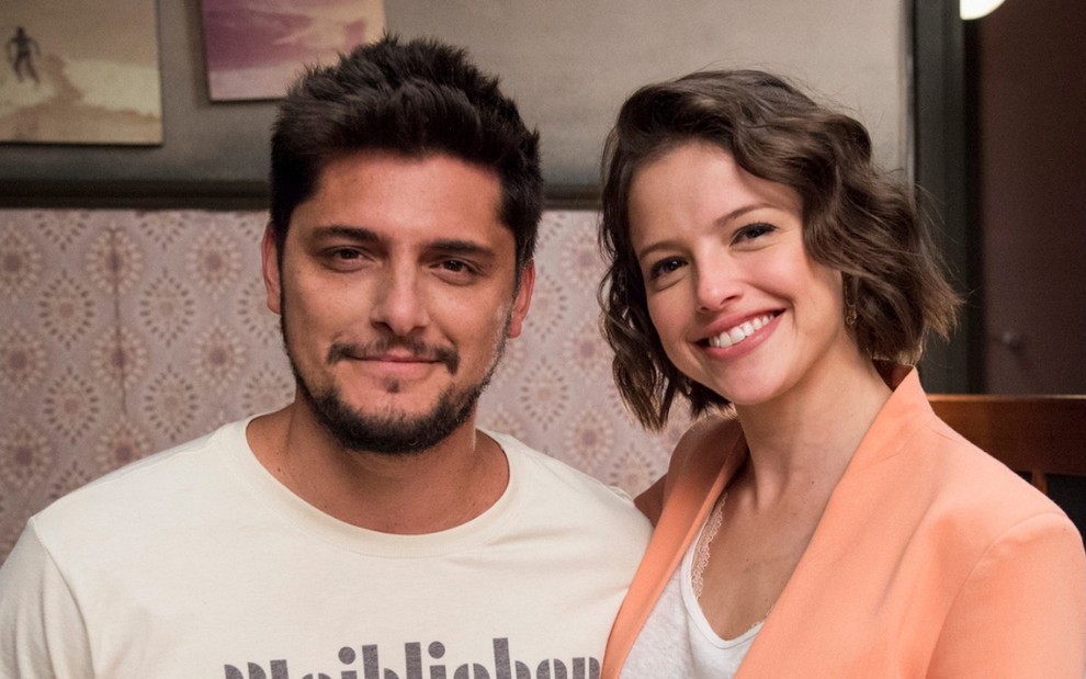 Os atores Bruno Gissoni e Agatha Moreira posam sorrindo para foto caracterizados como William e Josiane de A Dona do Pedaço