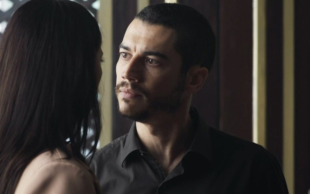 O ator Lee Taylor caracterizado como o personagem Camilo de A Dona do Pedaço, olha com desprezo para Paolla Oliveira, de costas na cena, como Virgínia