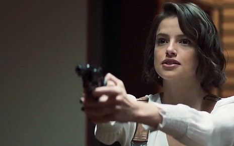A atriz Agatha Moreira com arma nas mãos em cena na novela das nove da Globo, A Dona do Pedaço