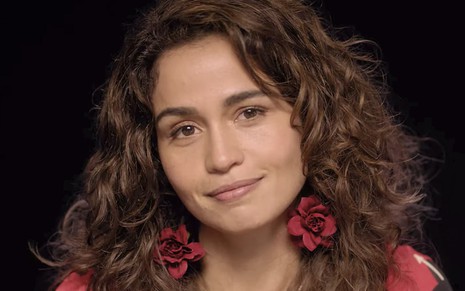A atriz Nanda Costa caracterizada como a personagem Érica de Amor de Mãe diante de um fundo preto