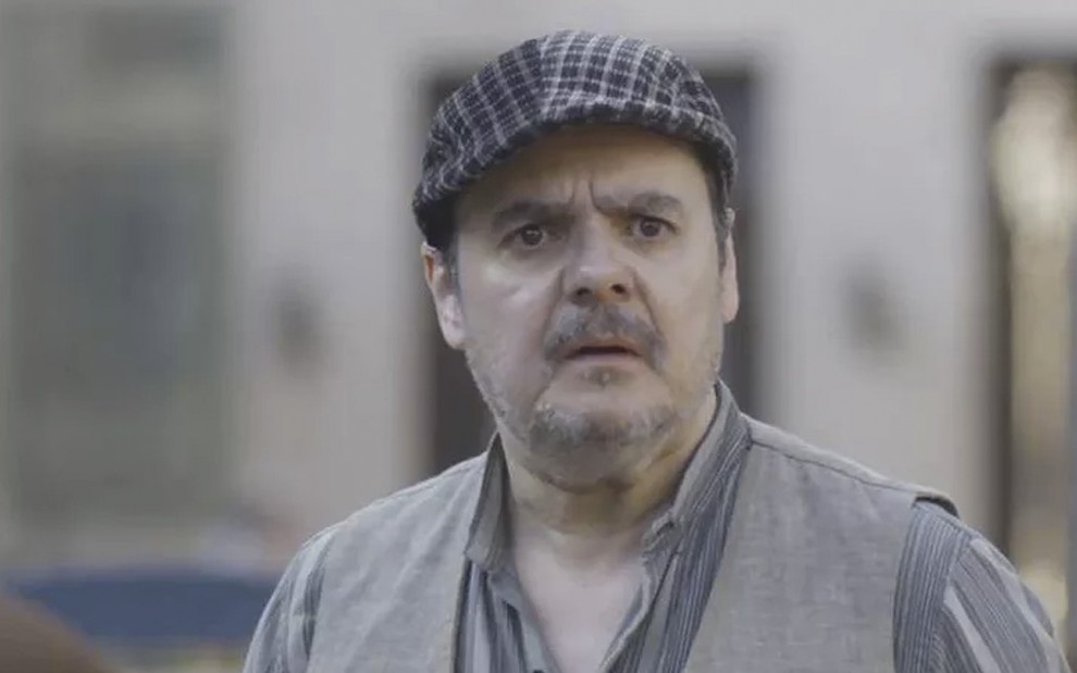 O ator Cássio Gabus Mendes caracterizado como Afonso em cena de Éramos Seis, de boina e suspensórios, ele tem a expressão de surpresa, com a boca aberta