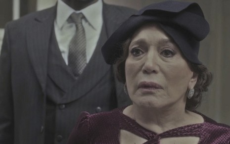 A atriz Susana Vieira caracterizada como a personagem Emília, com um chapéu preto e uma roupa vinho, em cena de Éramos Seis
