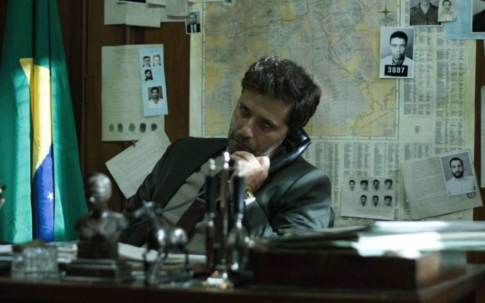 O ator Bruno Gagliasso como o personagem Lúcio no filme Marighella (2019), em um escritório