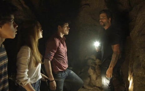 Feijão (Cauê Campos) leva Luz (Marina Ruy Barbosa) e Júnior (José Loreto) para a caverna em O Sétimo Guardião - Reprodução/TV Globo