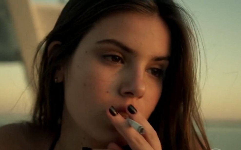 A atriz Camila Queiroz fumando um cigarro como a personagem Angel da novela Verdades Secretas, da Globo