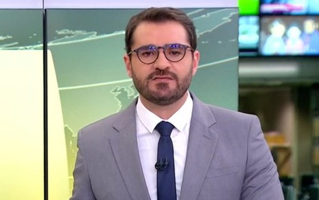 O jornalista Marcelo Cosme de terno e óculos no cenário do Jornal Hoje