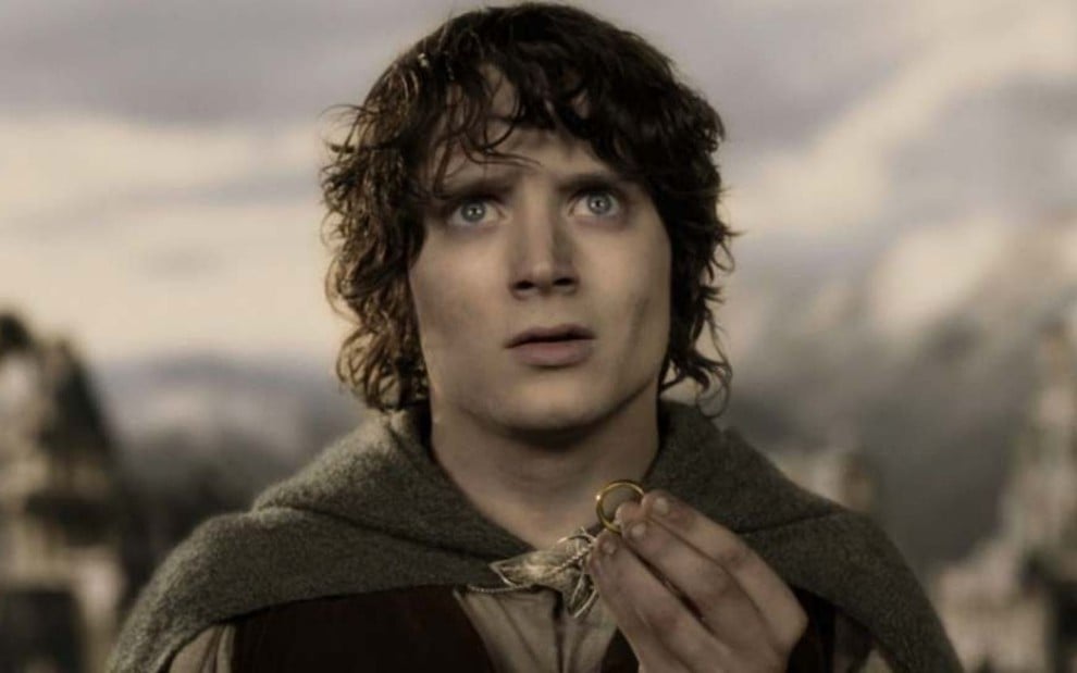 Personagem Frodo (Elijah Wood) segurando o Um Anel em cena do filme O Senhor dos Aneís