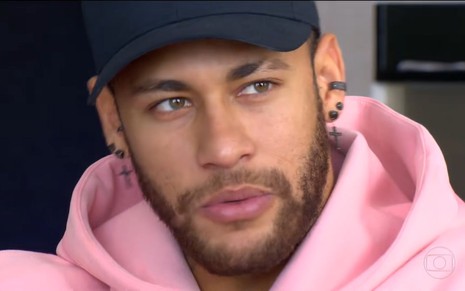 Foto de Neymar durante entrevista; ele usa boné preto e veste moletom cor de rosa