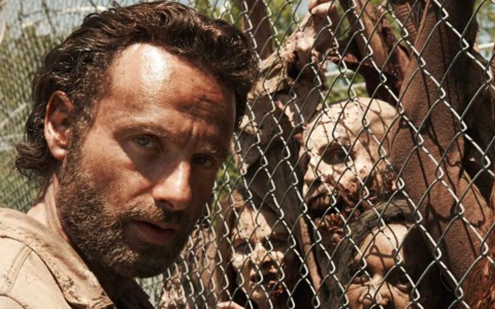 O ator Andrew Lincoln como Rick Grimes, ao lado de zumbis, em cena da série The Walking Dead - Divulgação/AMC