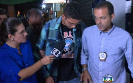 A repórter Bette Lucchese entrevista Caio Silva de Souza observada por policial do Rio de Janeiro - Reprodução/TV Globo