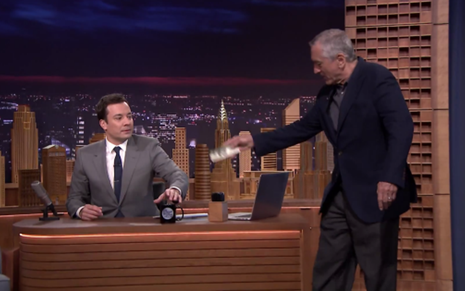 O ator Robert De Niro dá US$ 100 ao apresentador Jimmy Fallon no The Tonight Show de ontem (17) - Reprodução/NBC
