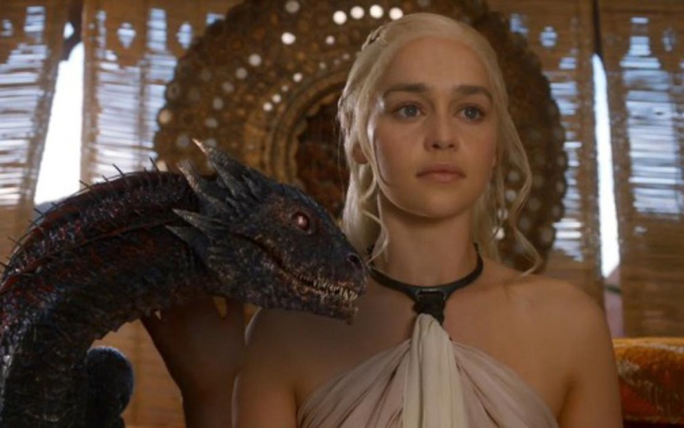 A atriz Emilia Clarke como Daenerys Targaryen ao lado de um dragão em Game of Thrones - Divulgação/HBO