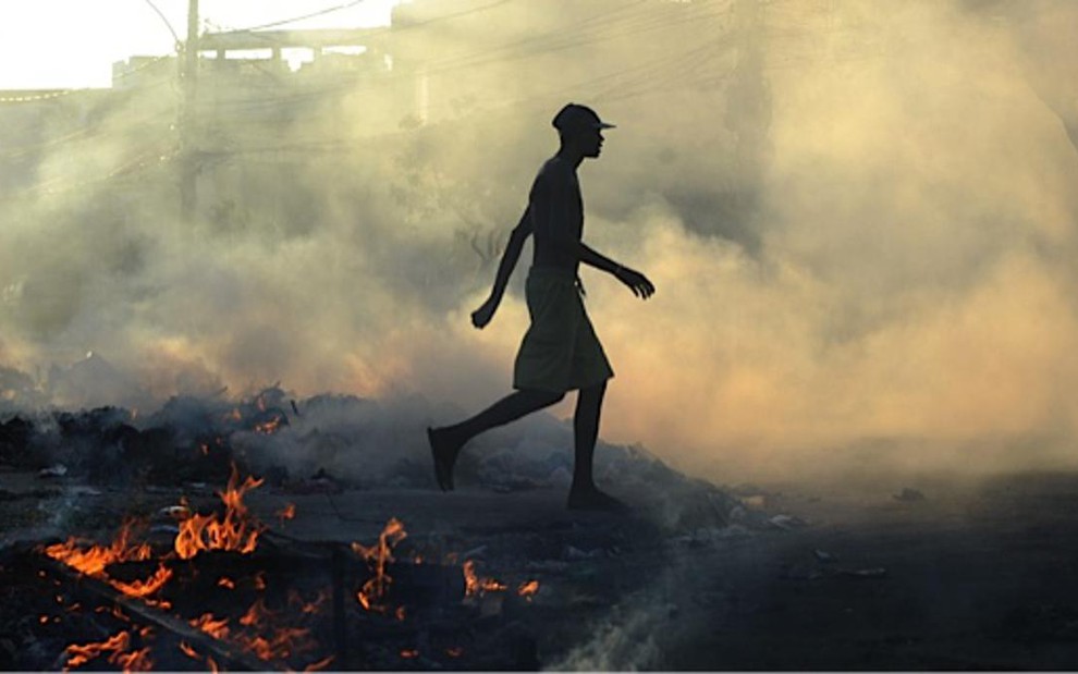 Jovem caminha entre objetos queimados em protesto contra a morte de moradora de morro do Rio - Fernando Frazão/Agência Brasil