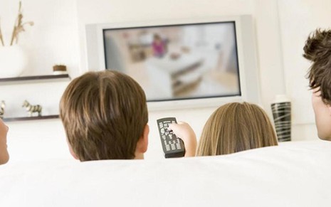 Família em frente à TV; valor da assinatura de canais em alta definição caiu 60% em três anos - Reprodução