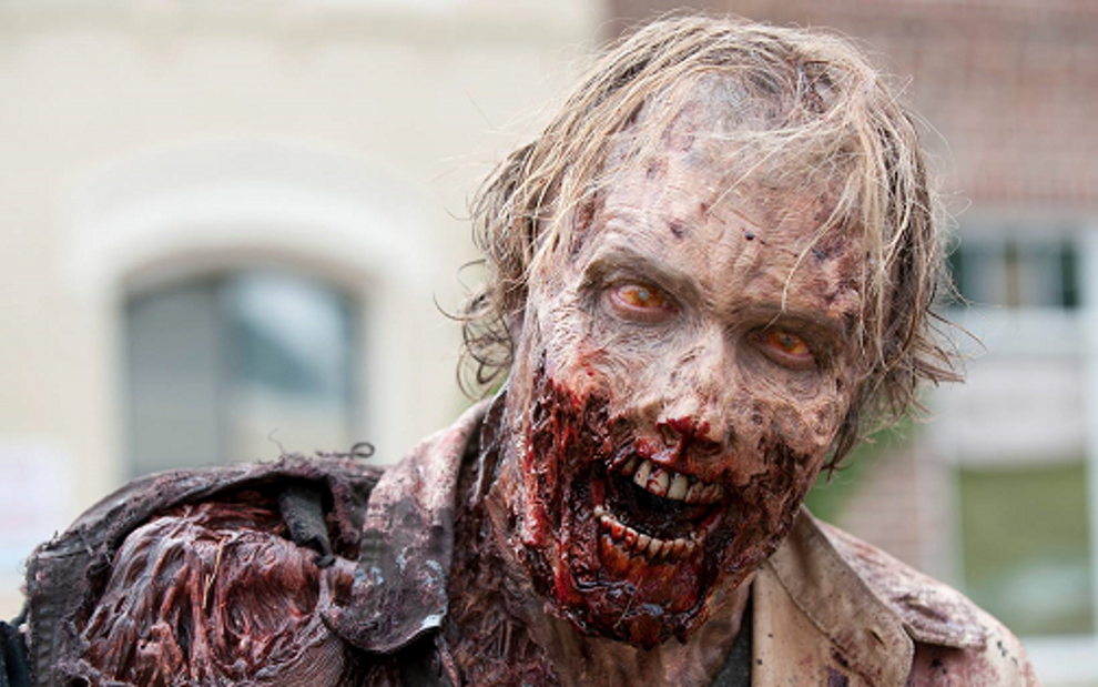 Figurante com rosto e ombros transformados por maquiagem em cena da série The Walking Dead - Fotos Divulgação/AMC