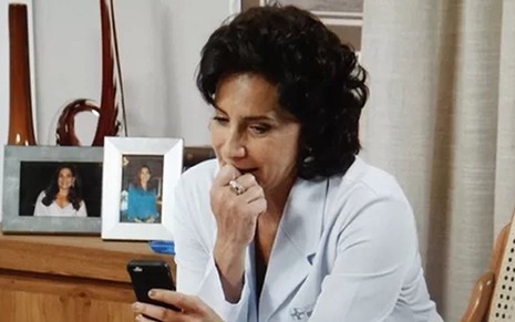 Adriana (Totia Meireles) vê foto de Laura na infância e dá dicas de que pode ser sua mãe - Reprodução/TV Globo