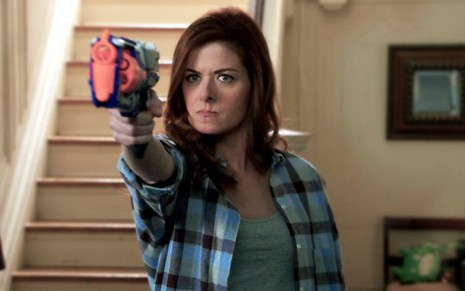 A atriz Debra Messing aponta uma arma de brinquedo em Os Mistérios de Laura, nova série da Warner  - Divulgação/NBC