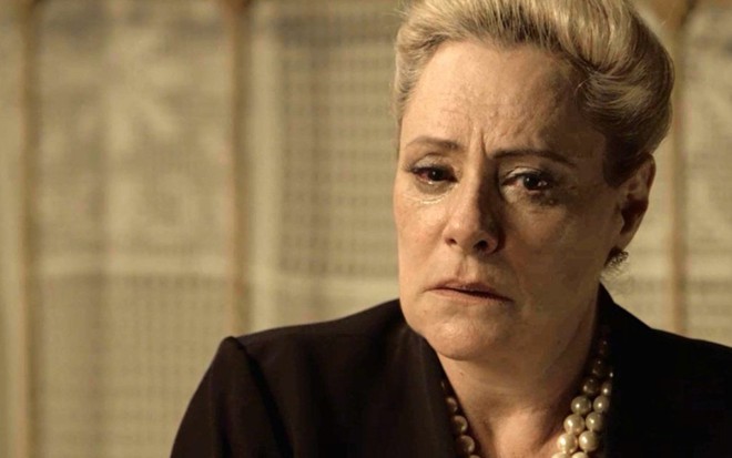 Mirtes (Elizabeth Savalla) se descuidará, e neto descobrirá que ela é o Tarja Preta de O Sétimo Guardião - Reprodução/Globo