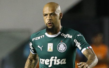 O jogador Felipe Melo, com uniforme do Palmeiras, corre no campo de futebol