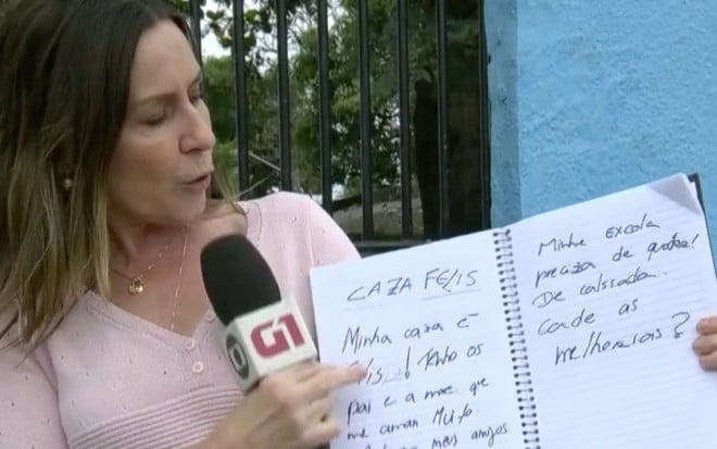 A repórter Susana Naspolini exibe caderno com erros de português em frente a escola municipal no Rio de Janeiro