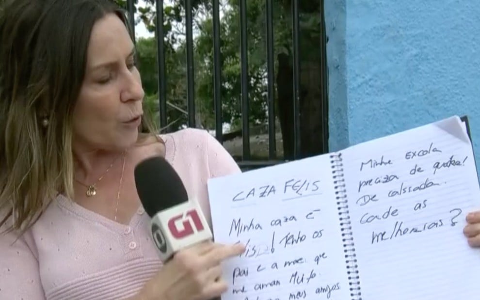 A repórter Susana Naspolini exibe caderno com erros de português em frente a escola municipal no Rio de Janeiro