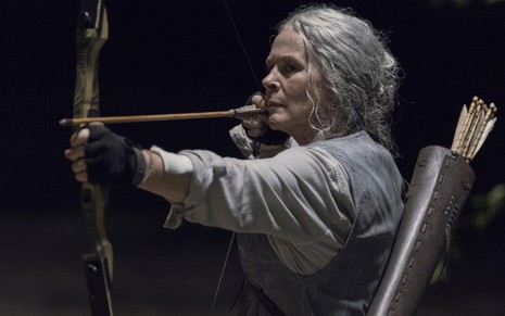 Melissa McBride segura um arco e flecha no sétimo episódio da décima temporada de Walking Dead