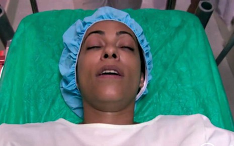 A atriz Samantha Schmütz aparece inconscientre em uma cama de hospital, com roupa de paciente, em cena de Totalmente Demais