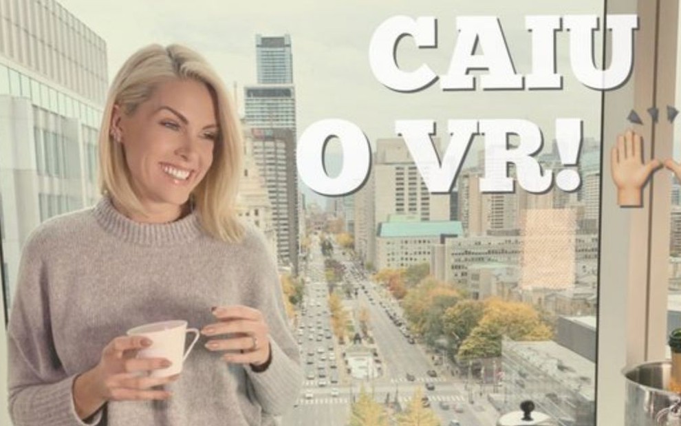 Foto da apresentadora Ana Hickmannn ao lado de uma mesa de café da manhã farta estampada com a frase "caiu o VR!", na frente de uma janela com uma avenida ao fundo