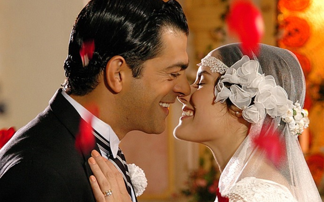Eduardo Moscovis, caracterizado como Rafael, e Liliana de Castro, a Luna, se beijam durante casamento em Alma Gêmea