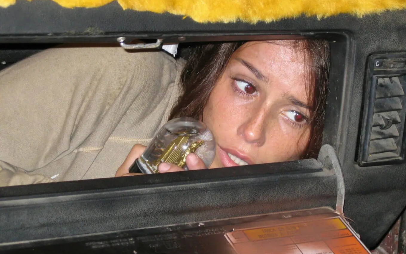 Sol (Deborah Secco) escondida no porta-luvas de um carro em cena de América (2005)